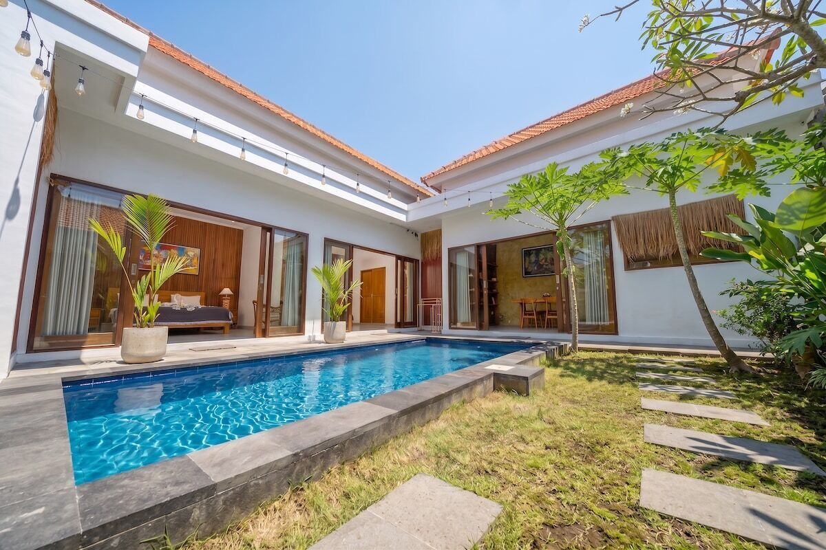 A modern house with a swimming pool, large windows, and a well-maintained garden.