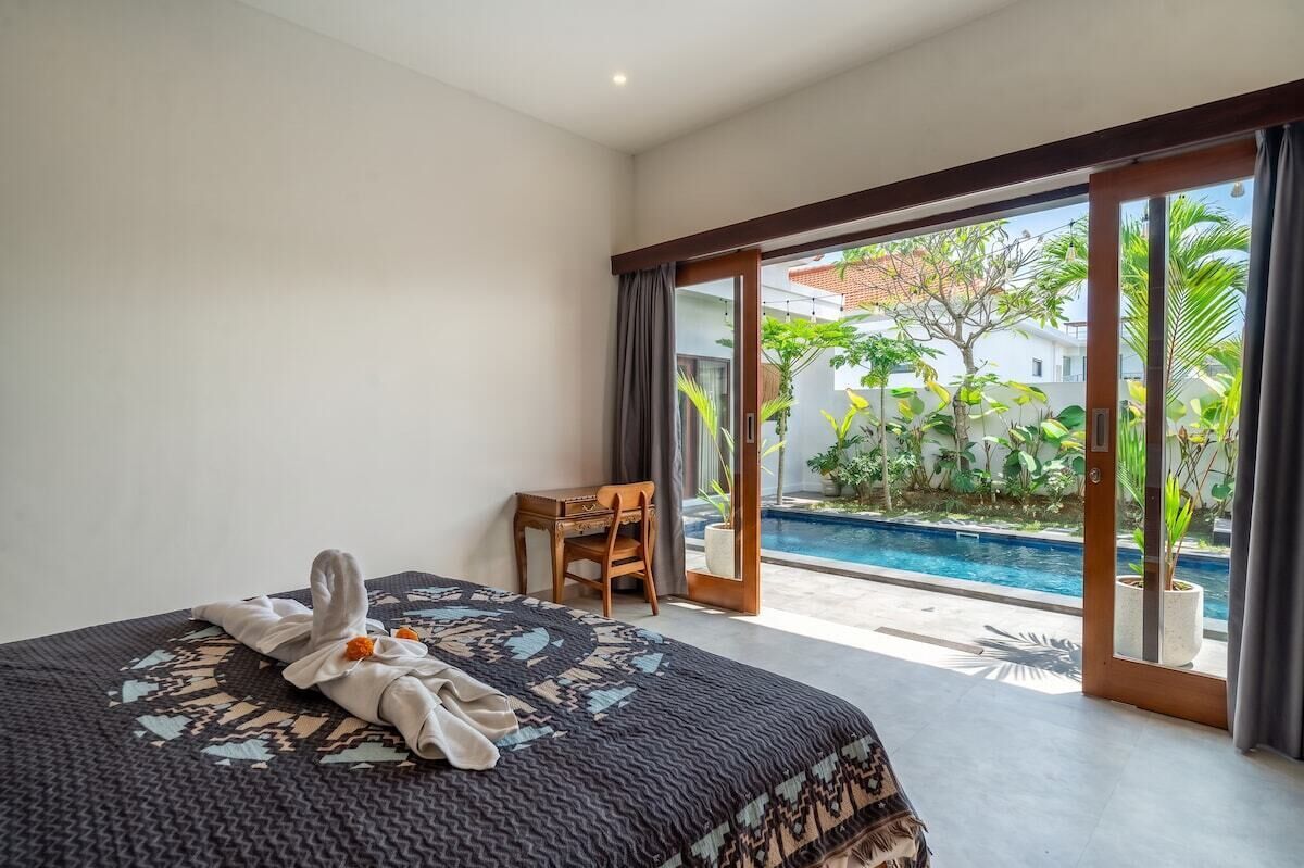 Ein Hotelzimmer mit Bett, Schreibtisch und Blick auf einen Swimmingpool.
