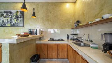 A modern kitchen with wooden cabinets, a stainless steel sink, and a black countertop.