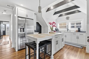 Una cocina moderna con una isla central, electrodomésticos de acero inoxidable y encimera negra.