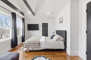Une chambre à coucher avec un lit, un téléviseur à écran plat, une porte et une fenêtre.