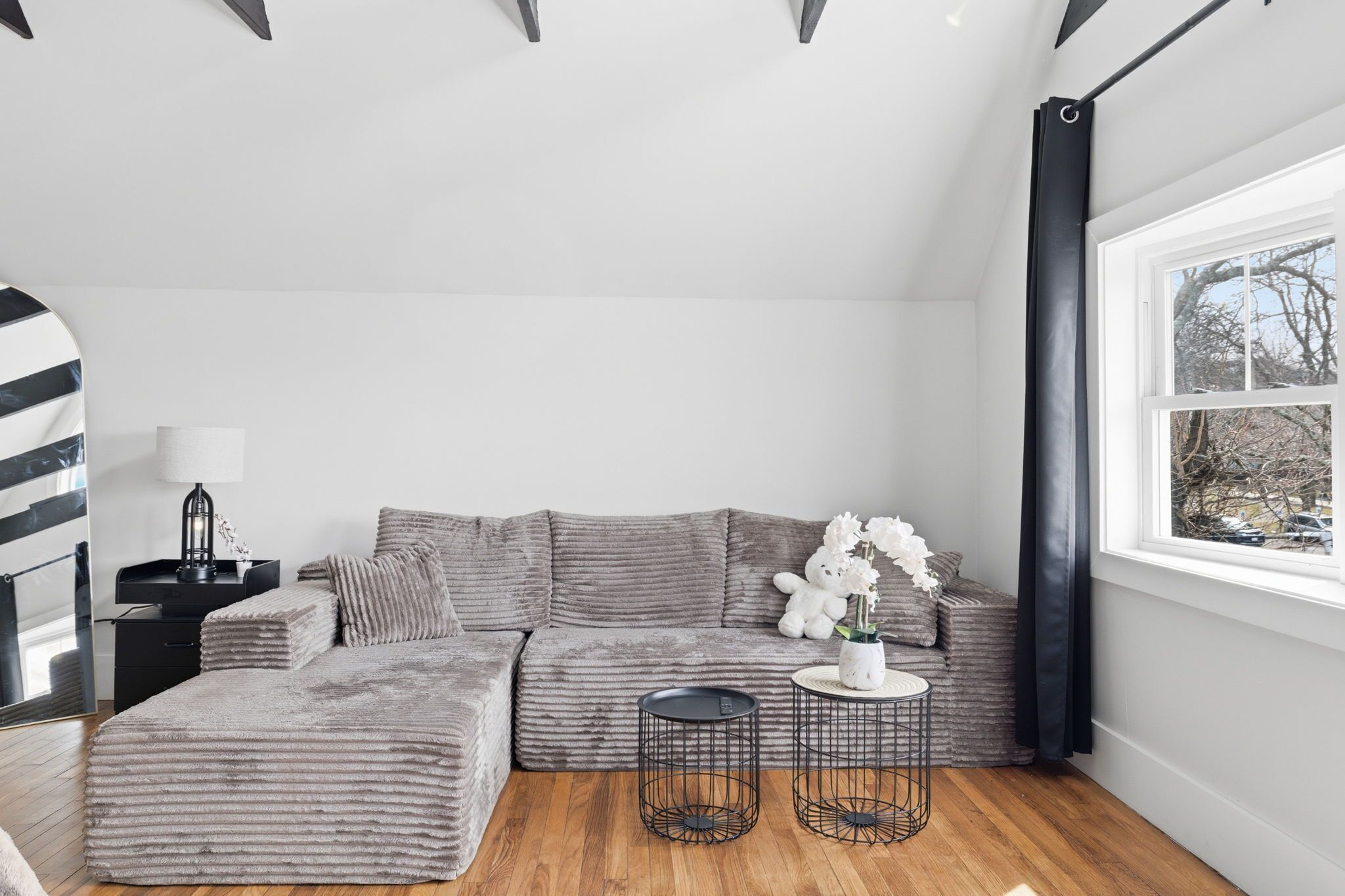 Una sala de estar moderna con un sofá modular, una mesita auxiliar, una lámpara y un ventanal con vistas.