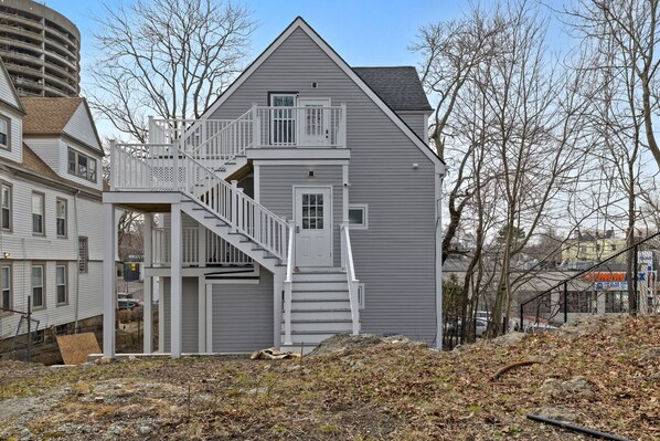 A two-story house with a central staircase and a small porch. - Bright and spacious 3BR Apt, gated 2 car parking, close to T station (Boston)