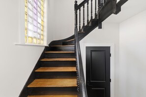 A staircase with wooden steps and black balusters leading to a door.