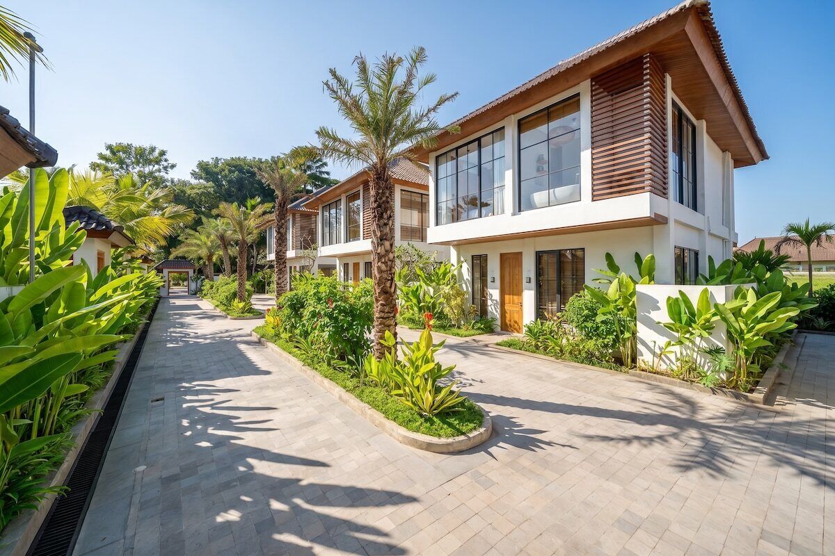 A residential area with modern houses, a paved walkway, and lush greenery.