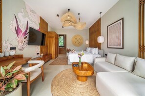 Una sala moderna con televisor de pantalla plana, un sofá, una mesa de centro y un comedor con mesa y sillas de madera.