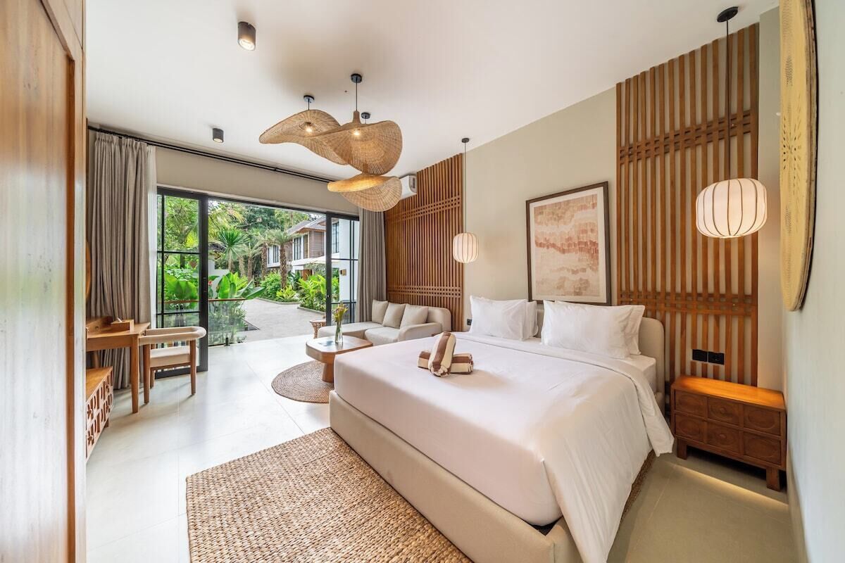 Un dormitorio moderno con una cama grande, un escritorio y vistas al verdor exterior.