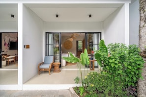 A modern interior with a seating area, a large window, and a plant. - Serene 1BR • Ubud • Pool • Private Kitchen & Patio (Gianyar Regency)