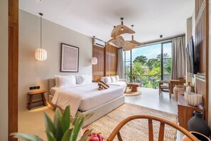 A modern bedroom with a large bed, a sitting area, and a view of greenery outside. - Luxe 1BR in Ubud w Pool, Private Kitchen & Balcony (Gianyar Regency)