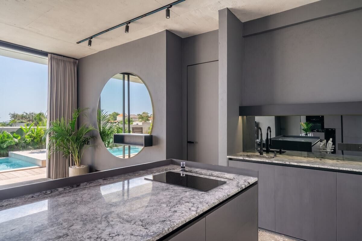 Cocina moderna con una isla grande, electrodomésticos integrados y vistas a una piscina.