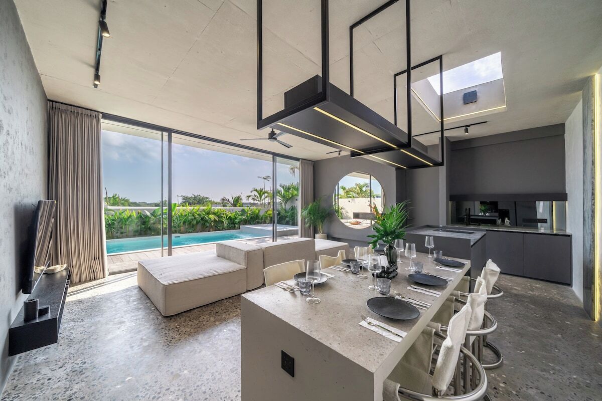 Un interior moderno con comedor, cocina y vista a la piscina.