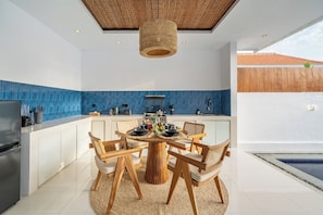 A modern kitchen with a round dining table, white cabinets, and blue backsplash. - Tropical 2BR Villa in Canggu w Pool & Beach Nearby (Kuta Utara)
