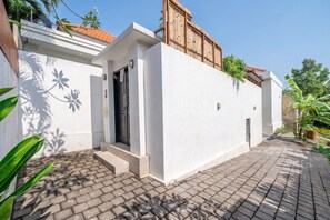 A modern building with a white facade, a wooden fence, and a paved walkway. - Tropical 2BR Villa in Canggu w Pool & Beach Nearby (Kuta Utara)