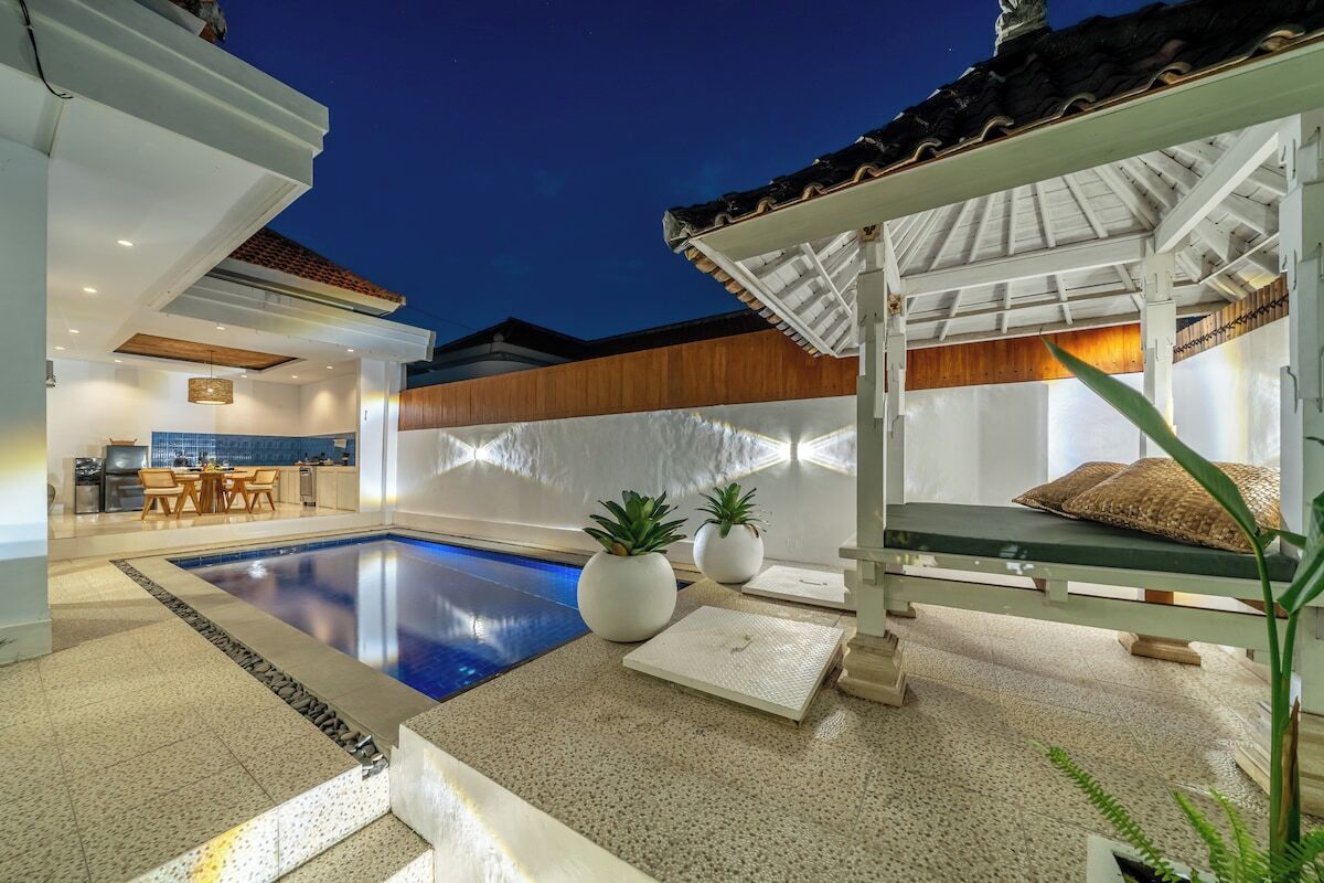 A modern outdoor pool area with a lounge chair and potted plants.