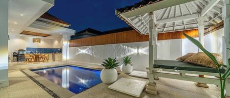 A modern outdoor pool area with a lounge chair and potted plants.