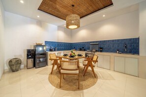 A modern kitchen with a round dining table, wooden chairs, and a blue backsplash. - Tropical 2BR Villa in Canggu w Pool & Beach Nearby (Kuta Utara)