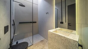Ein modernes Badezimmer mit einer Glaskabine zur Dusche, einer freistehenden Badewanne und einem großen Spiegel.