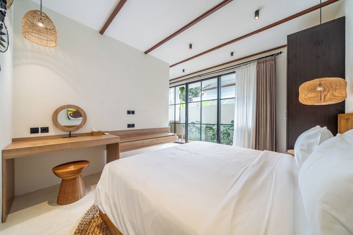 Une chambre à coucher moderne avec un grand lit, une table de chevet en bois, un miroir rond et un luminaire suspendu.