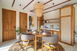 Un coin repas comprenant une table ronde, quatre chaises et un luminaire suspendu.