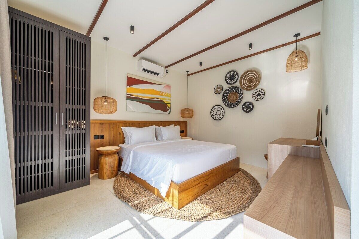 A bedroom with a bed, bedside tables, a wardrobe, wall decor, and a built-in bench.