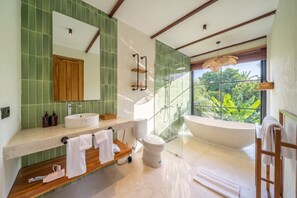 Ein modernes Badezimmer mit einer großen Badewanne, einer separaten Duschkabine und einem Waschtisch mit Spiegel und Waschbecken.