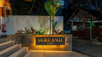 A sign for 'Sacred Jungle by anthro' with steps leading up to it, surrounded by tropical plants.