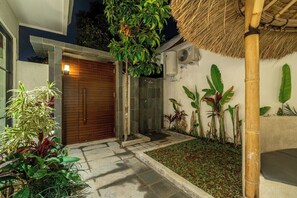 L’extérieur d’une maison moderne, avec une porte en bois, une porte en verre et un toit de chaume.