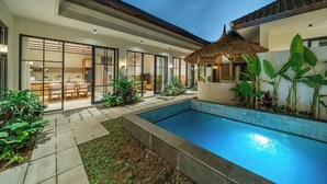 Una casa moderna con piscina, comedor y una estructura de techo de paja.