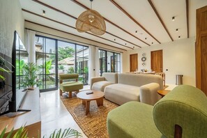 Un salon moderne comprenant un canapé, des fauteuils, une table basse et un téléviseur.