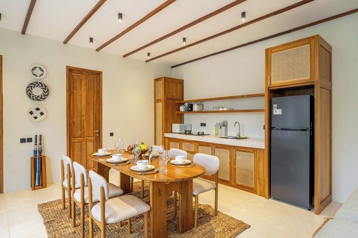 A modern kitchen with wooden cabinetry, a black refrigerator, and a dining area with a wooden table and chairs.