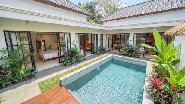 Una casa moderna con piscina, ventanas amplias y un jardín cuidado.