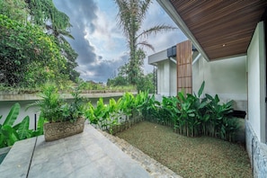 A modern house with a garden, a concrete pathway, and a wooden ceiling. - Tropical 3BR Villa in Ubud w Pool, Patio & Garden (Gianyar Regency)