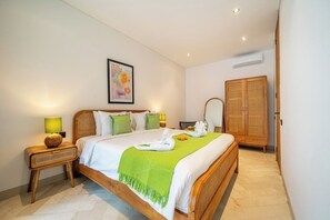 A neatly arranged bedroom with a bed, bedside tables, a wardrobe, and a framed picture on the wall. - Tropical 3BR Villa in Ubud w Pool, Patio & Garden (Gianyar Regency)