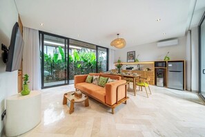 A modern living room with a sofa, coffee table, and a dining area with a table and chairs. - Tropical 3BR Villa in Ubud w Pool, Patio & Garden (Gianyar Regency)