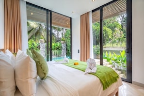 A hotel room with a bed, a view of a garden, and a pool. - Tropical 3BR Villa in Ubud w Pool, Patio & Garden (Gianyar Regency)