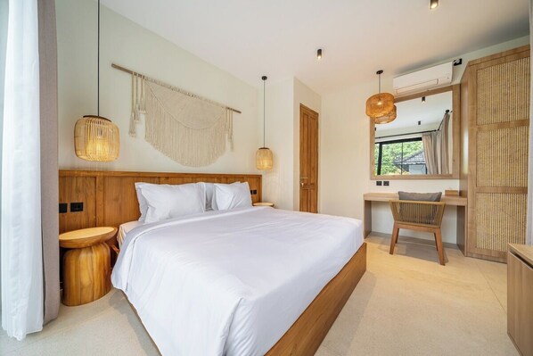 Een moderne slaapkamer met een groot bed, nachtkastjes, een houten hoofdbord, een bureau en een spiegel.