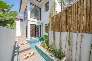 Een modern huis met een zwembad, grote ramen en een houten omheining.
