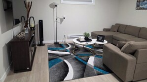 Un saló modern amb un sofà, una taula de centre, una televisió i una catifa decorativa.