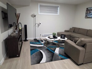 Un soggiorno moderno con un divano, un tavolino, una TV e un tappeto decorativo.
