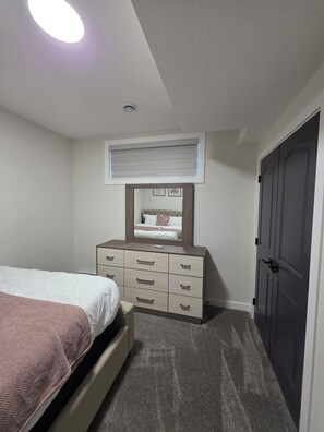 A bedroom with a bed, dresser, and a door.
