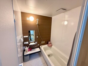 Ein Badezimmer mit einer Badewanne, einem Spiegel, einem Handtuchhalter und einem Ablagefach für Toilettenartikel.