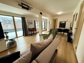 Ein modernes Wohnzimmer mit einer Couch, einem Esstisch und einer Küchenzeile.