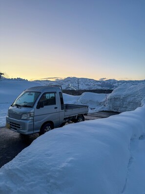 A silver pickup truck parked on a snow-covered road with mountains in the background.