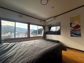 Ein Schlafzimmer mit einem großen Bett, einem Fenster mit Bergblick und einem japanischen Wellenbild an der Wand.