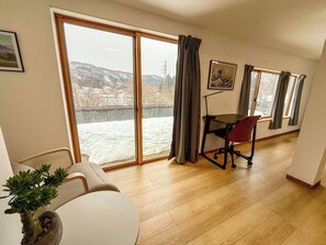 A room with a large sliding glass door leading to a snowy outdoor area, a dining table with chairs, and a potted plant.