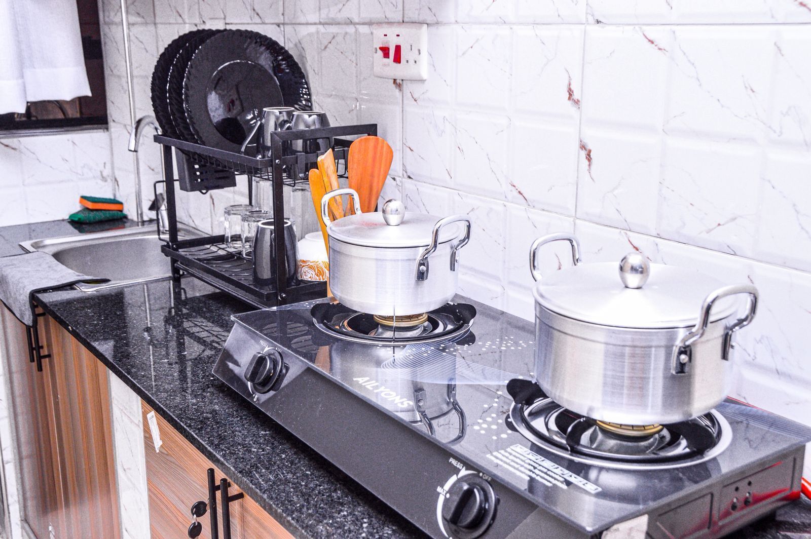 Una cocina con dos estufas a gas, un escurreplatos y un hervidor.