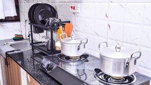 A kitchen with two gas stoves, a dish rack, and a kettle. - Alasiri Apartments Utawala (Nairobi)