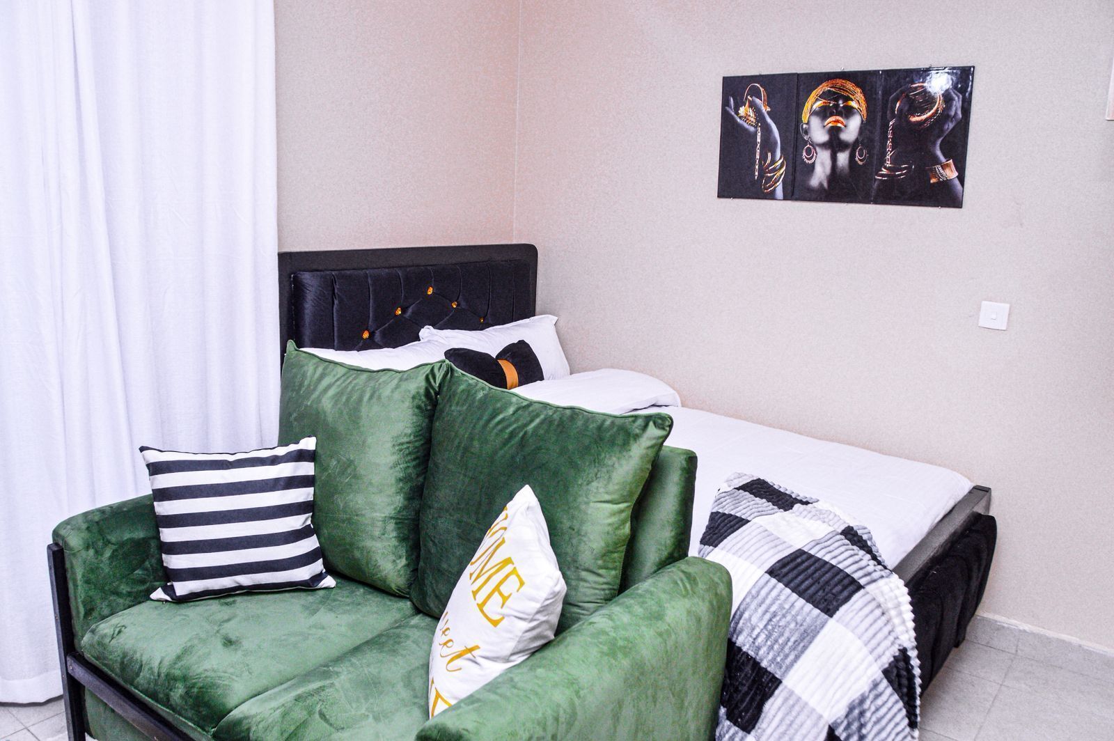 Un dormitorio con una cama, un sofá verde y un cuadro en la pared.