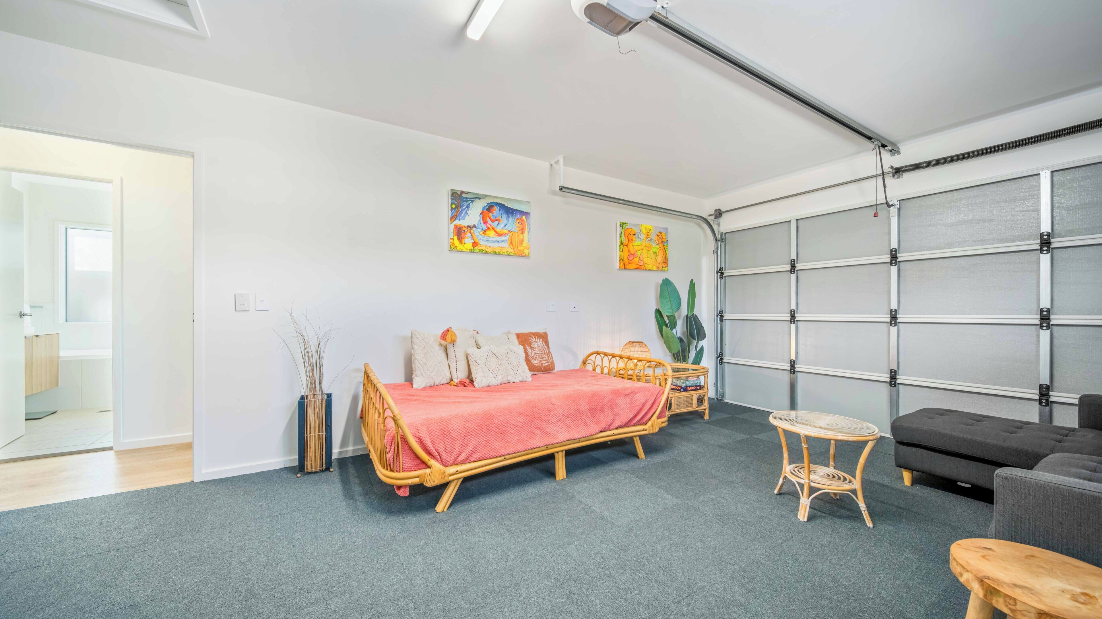 A room with a bed, a sofa, a small table, and a wall-mounted shelf.