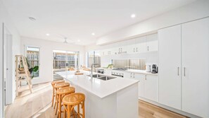 Une cuisine moderne dotée d’un îlot central, d’appareils électroménagers en acier inoxydable et de meubles de rangement blancs.